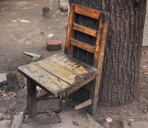 Старый стул на трех ножках у дерева