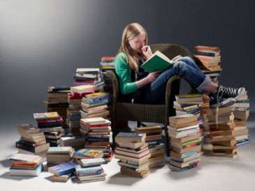 Девочка читает книгу, вокруг много книг
